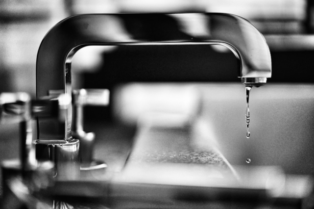 A silver faucet with water dripping from it.