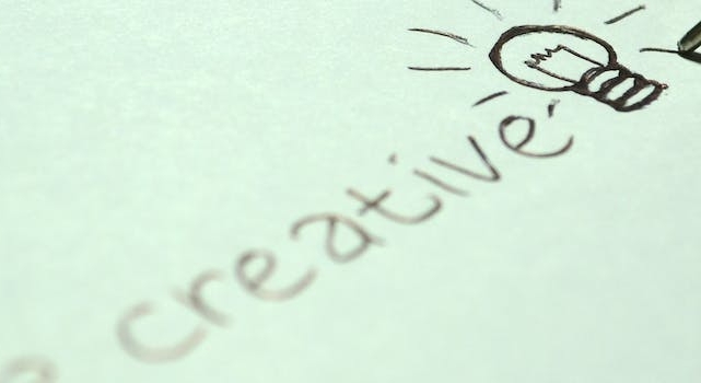 Close-up of a hand writing “be creative.”